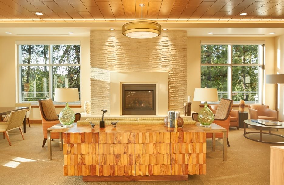 A modern living room with a central fireplace and wooden furniture, featuring neutral tones and elegant lighting.