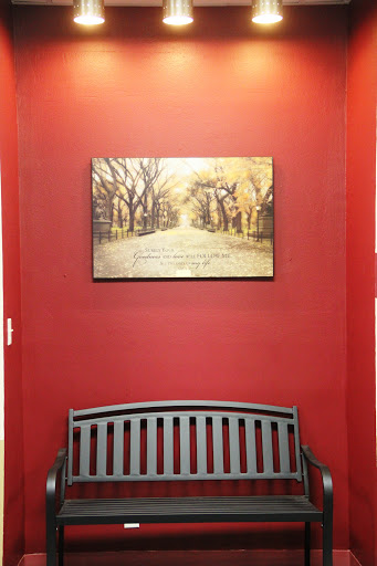 A cozy interior space featuring a red wall and a serene painting above a wooden bench.