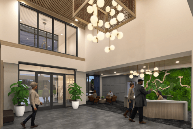 A modern lobby with a chandelier and people at the reception desk.