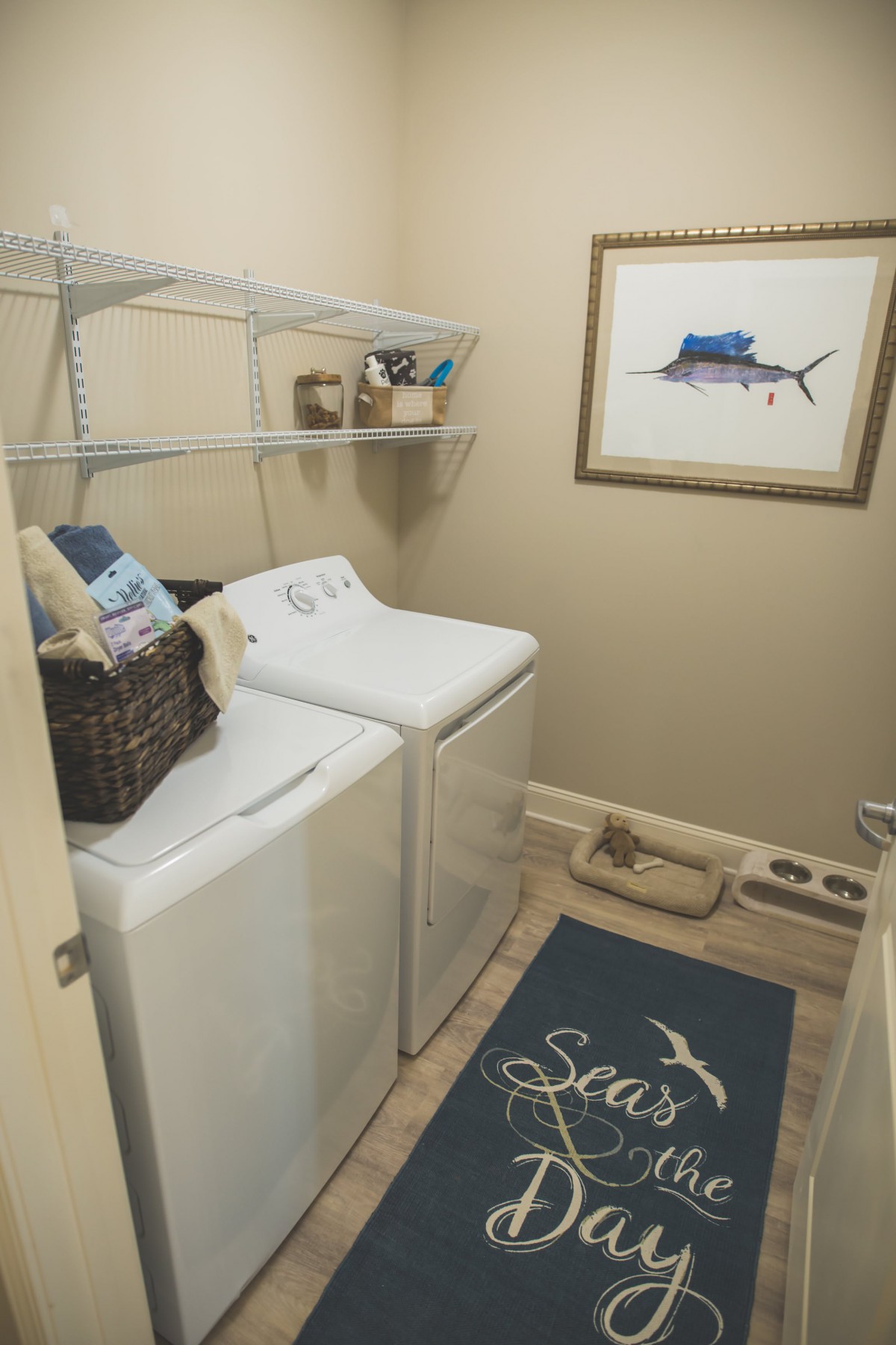 Cozy laundry room with a washer, dryer, and wall shelves for storage.