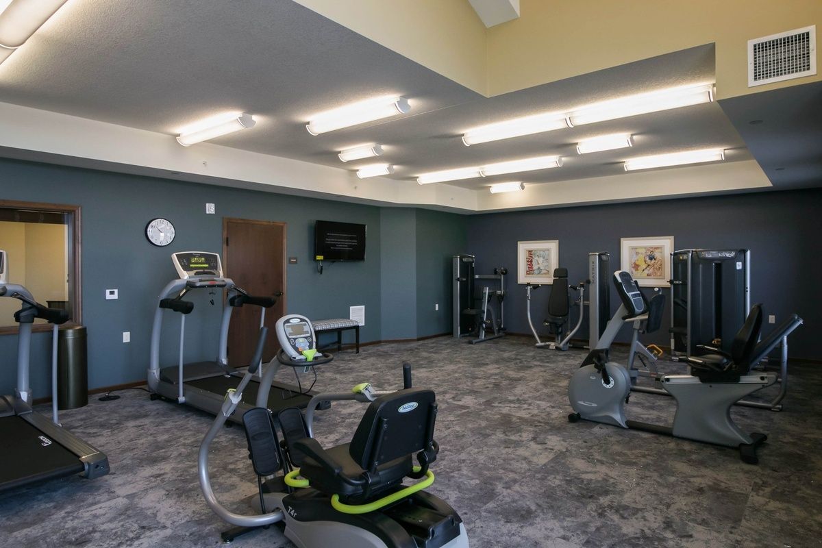 A well-lit gym equipped with various exercise machines and a modern interior.
