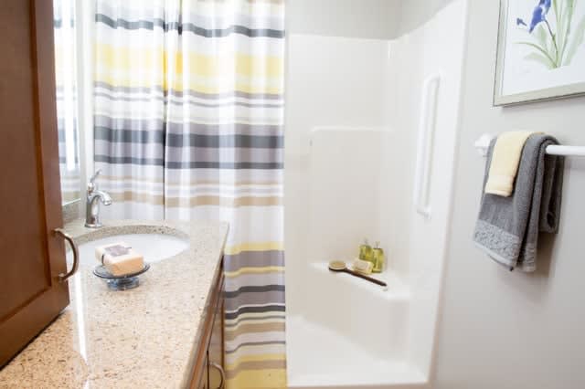 A modern bathroom with a striped shower curtain and neatly arranged sink.