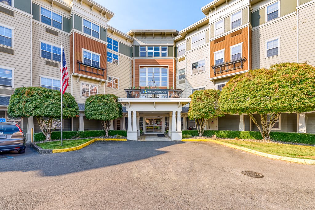 A multi-story residential building with a welcoming entrance and neatly trimmed trees.