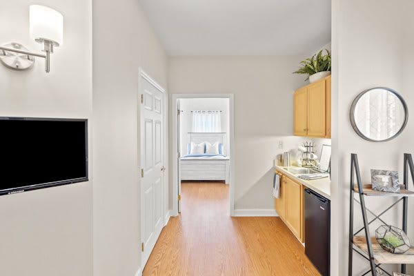 A bright, modern apartment kitchen with wooden floors and light-colored cabinets.