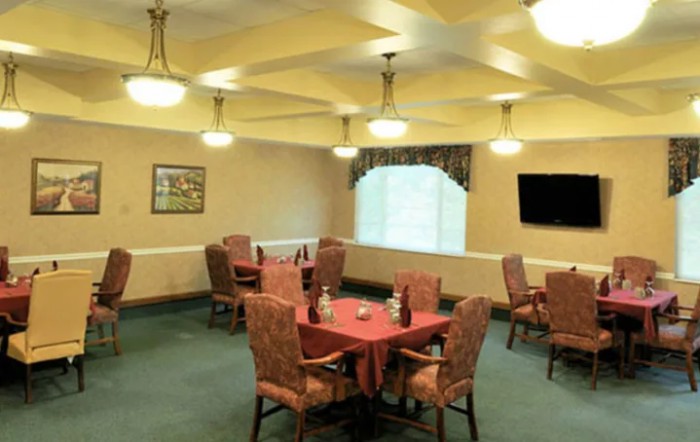 A well-lit dining room with neatly arranged tables and chairs.
