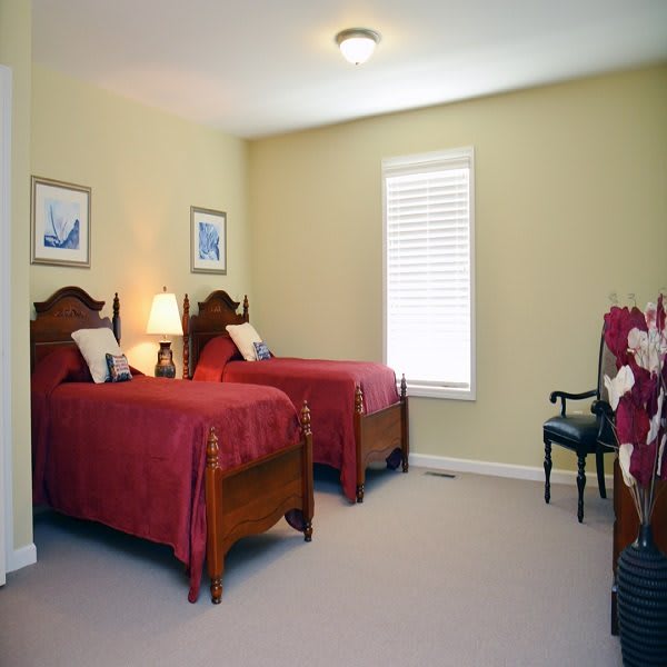 A cozy bedroom with two traditional wooden beds, a lamp, and artwork on the walls.