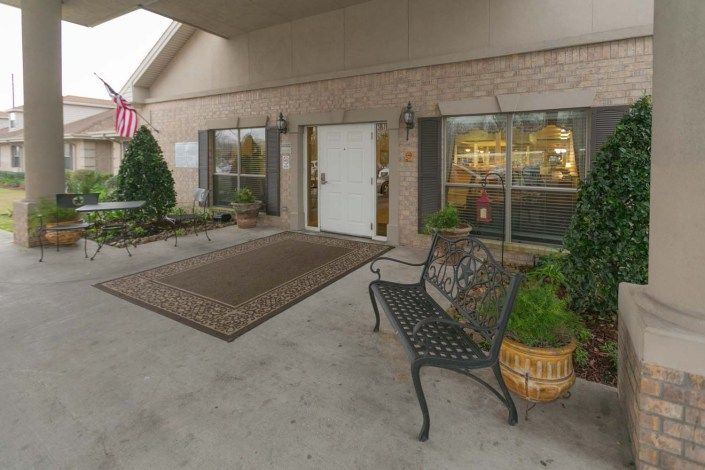 An inviting entrance with a bench and decorative plants outside a building.