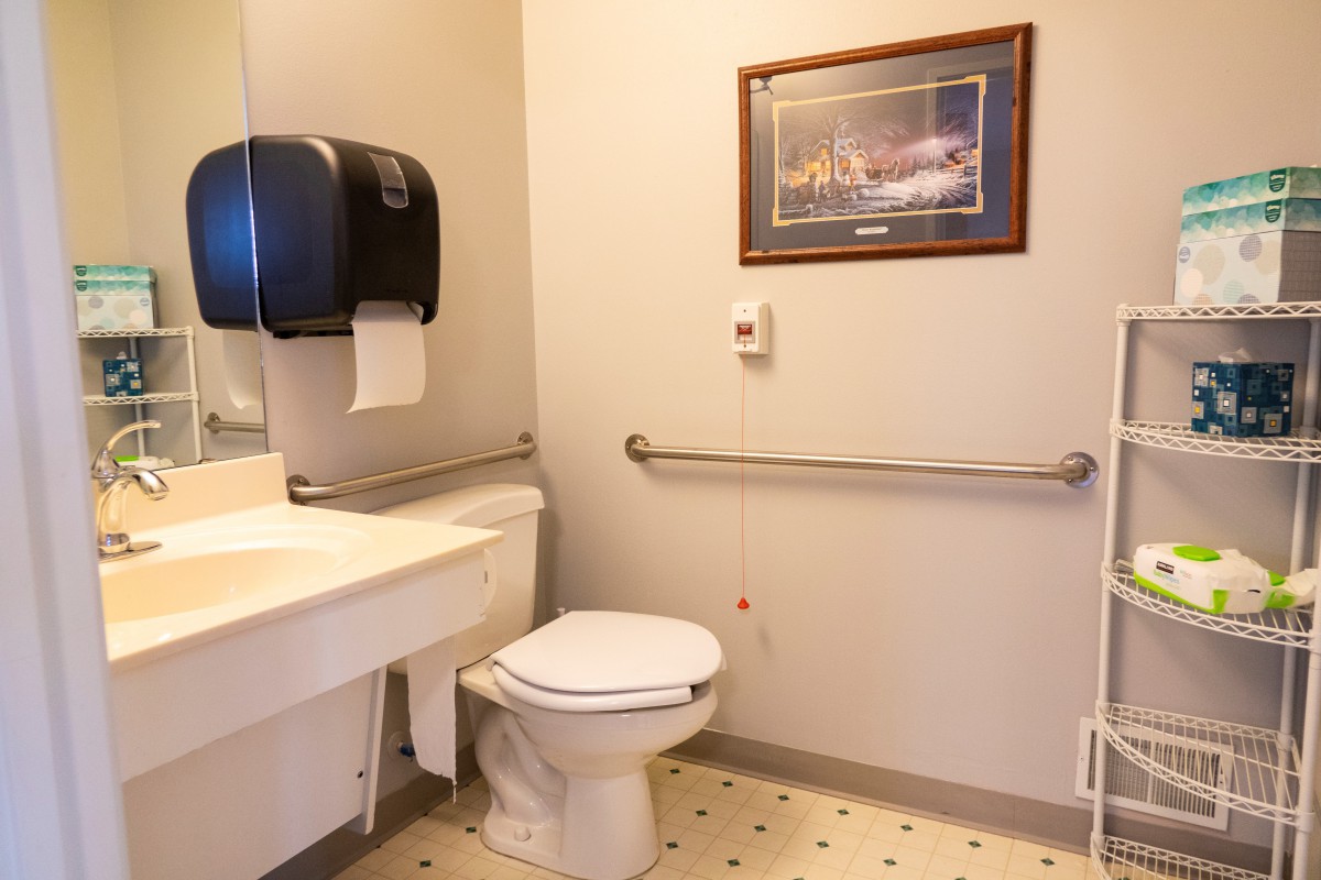 A clean bathroom with a toilet, sink, and safety grab bars.