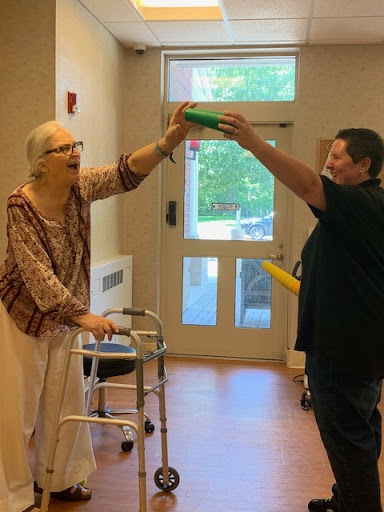 A joyful interaction between an elderly individual and a caregiver, engaging in a playful activity indoors.
