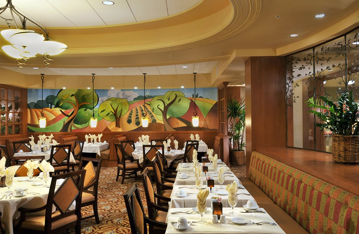 Elegant restaurant interior with neatly arranged tables and a colorful mural on the wall.