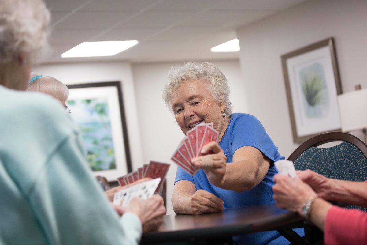Elderly woman enjoying a card game with friends.