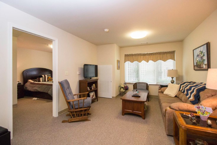 A cozy living room with a sofa, rocking chair, and television.