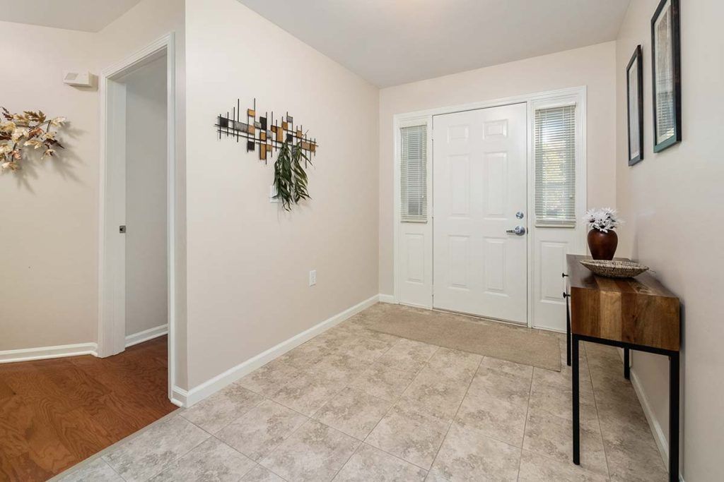 A tidy entryway featuring a white door, carpeted floor, and minimal decor.