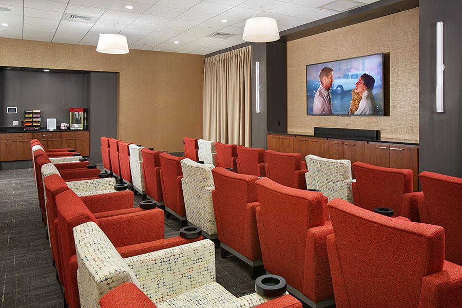 A modern movie theater with red seating and a large screen displaying a film.