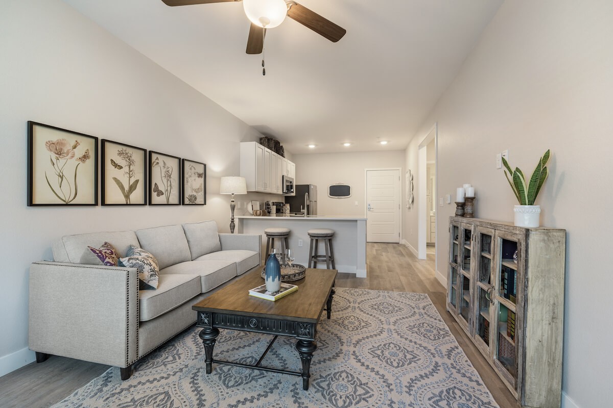 A contemporary open floor plan living room with a comfortable sofa and coffee table, seamlessly connected to a modern kitchen.