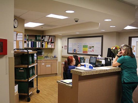 A hospital reception area with staff working at computers behind a desk.
