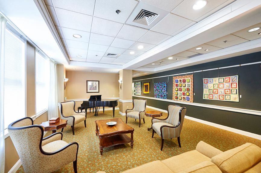 A cozy room with a grand piano, seating area, and artwork on the walls.