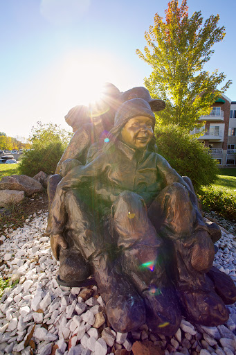A bronze sculpture depicting joyful children playing together, illuminated by the warm sunlight.