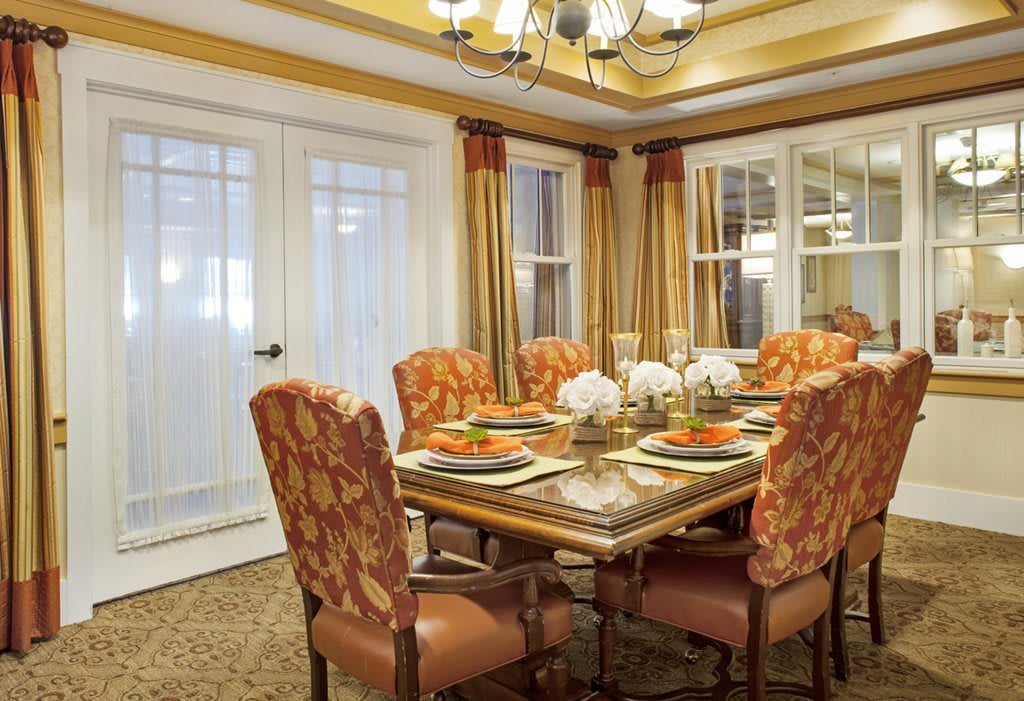 A beautifully decorated dining room with a set table and upholstered chairs.