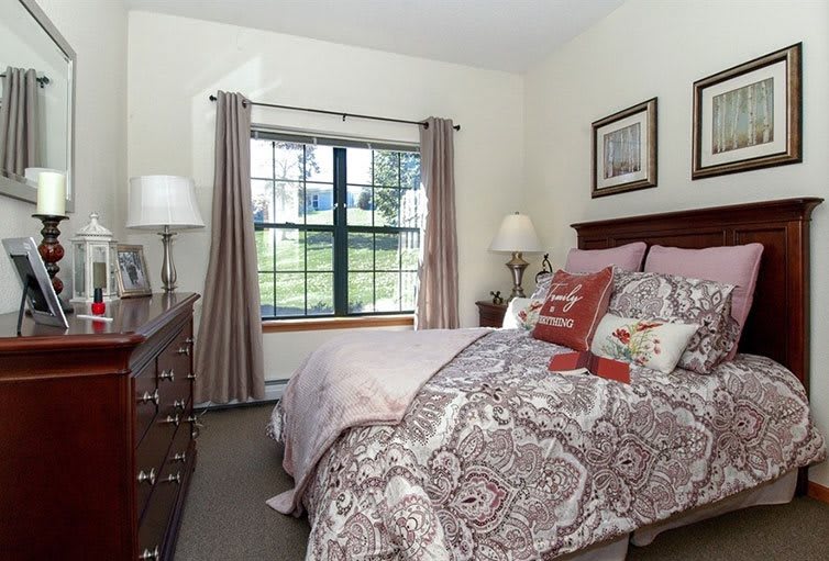 A cozy bedroom with a neatly made bed, large window, and stylish decor.
