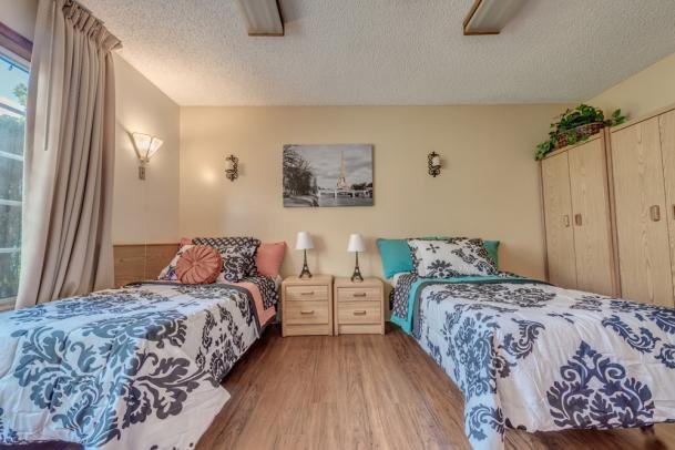 A cozy bedroom featuring two twin beds with floral bedding, a shared nightstand, and decorative wall art.