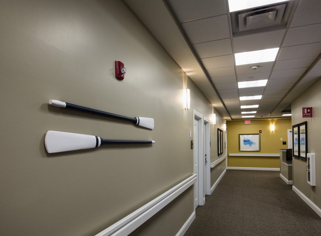 A hallway with decorative oars mounted on the wall and framed artwork.