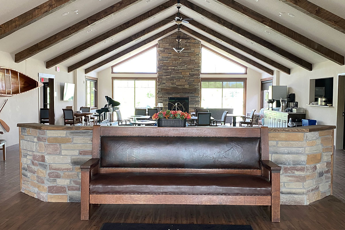 A cozy living room with a vaulted ceiling, featuring a central fireplace and a wooden bench in the foreground.