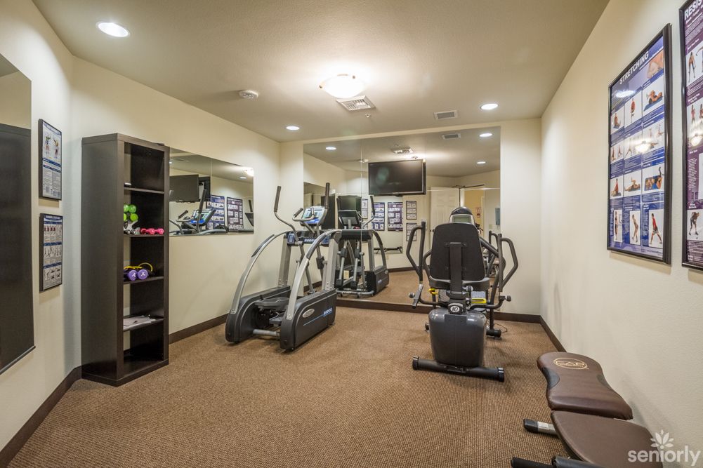 A compact indoor gym with various exercise equipment, including an elliptical and weight machine.
