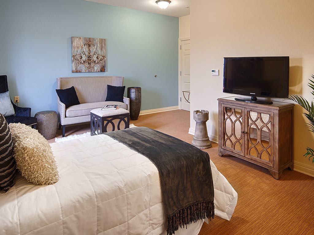 A cozy bedroom with a bed, couch, and television.