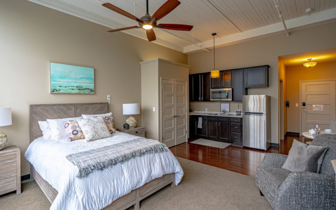 A cozy studio apartment featuring a comfortable bed, a kitchenette, and modern interior design elements.