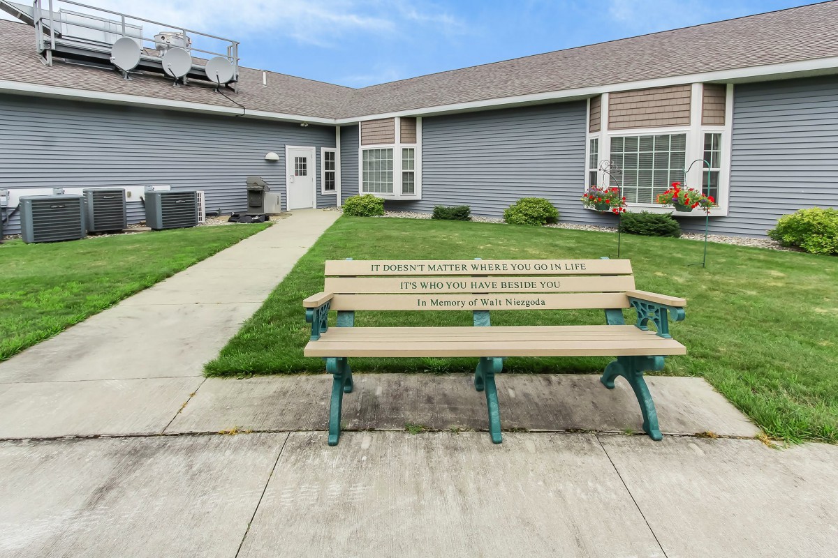 A wooden bench is placed in front of a modern building with well-maintained landscaping.