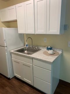 A compact kitchen with a white refrigerator, sink, and cabinetry.