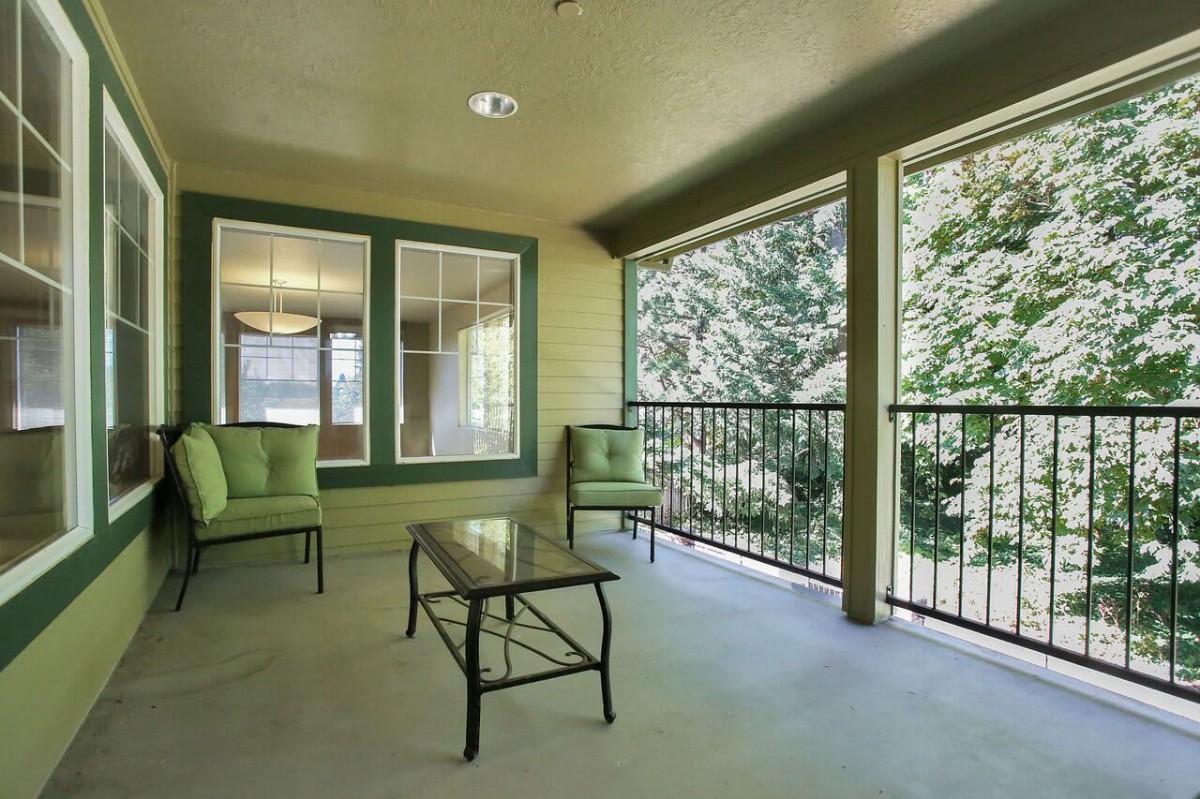 A spacious outdoor patio with comfortable seating and a view of surrounding greenery.