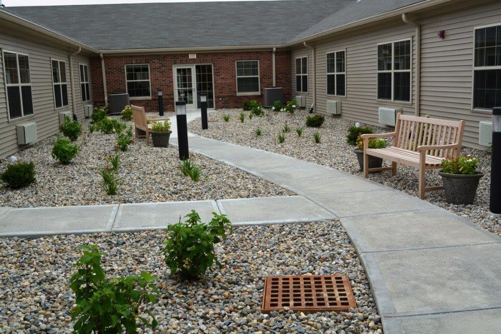 A landscaped courtyard with a pathway, benches, and shrubbery surrounded by rocks.