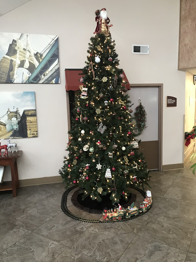 A beautifully decorated Christmas tree in a lobby, adorned with ornaments and surrounded by holiday cheer.