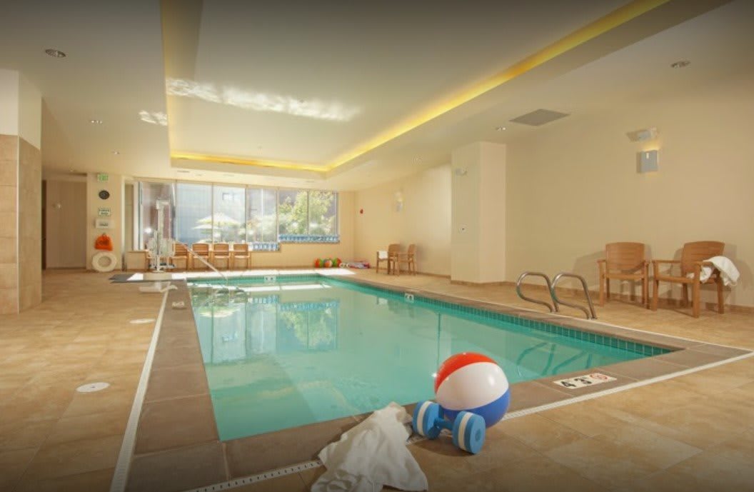 An inviting indoor swimming pool with chairs, a beach ball, and towels nearby.