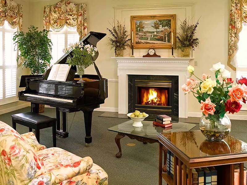 A cozy living room featuring a grand piano and a warm fireplace.