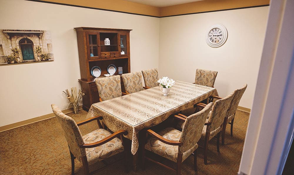 A cozy dining room featuring a large table with upholstered chairs and a cabinet.