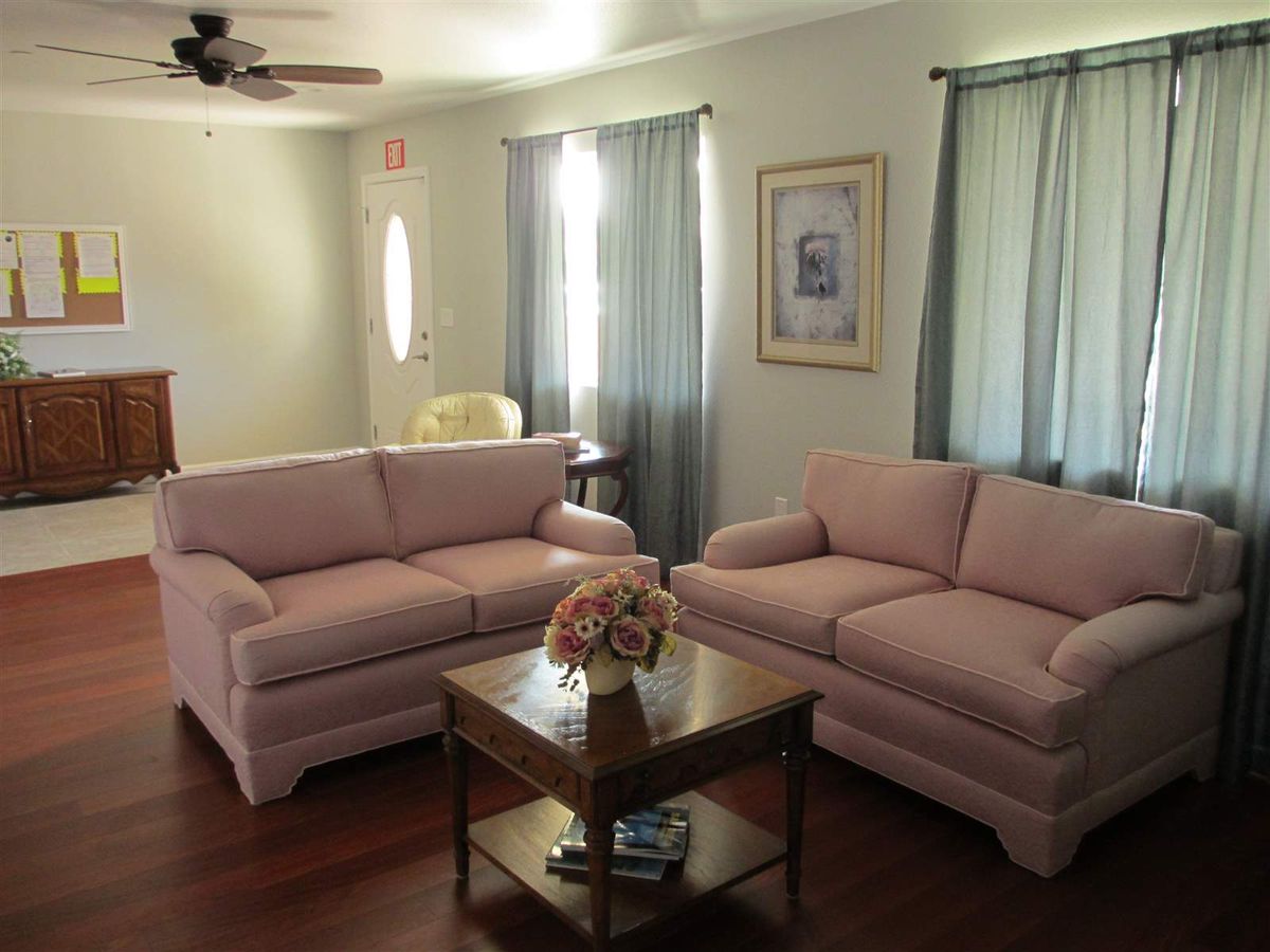 A cozy living room with two pink sofas and a wooden coffee table, complemented by light blue curtains.