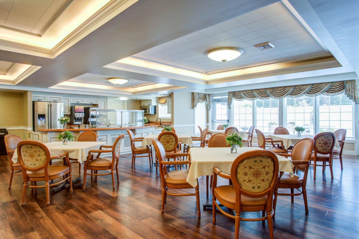 A spacious dining area with neatly arranged tables and chairs, featuring large windows and elegant lighting.