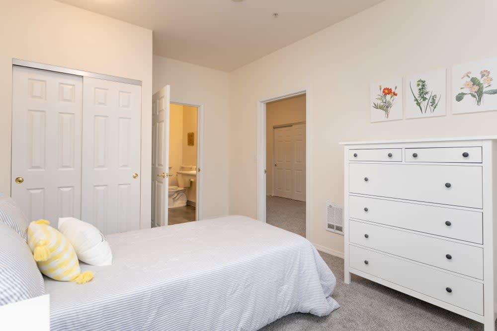 A bright and minimalistic bedroom with white furniture and bedding.