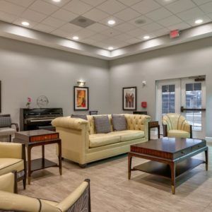 A well-furnished living room with sofas, a piano, and decorative artwork.