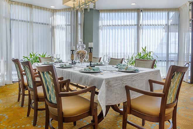An elegantly set dining room table with chairs and decorative candles.