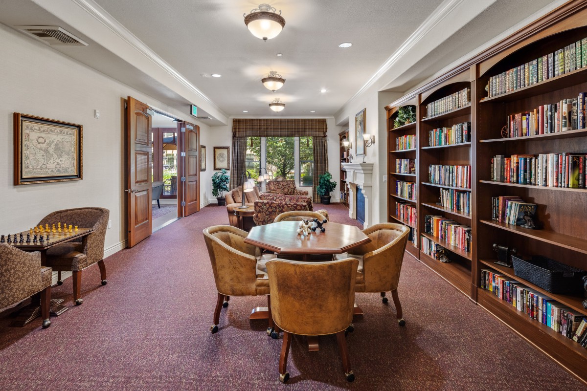 A cozy library room with bookshelves, comfortable seating, and elegant lighting.