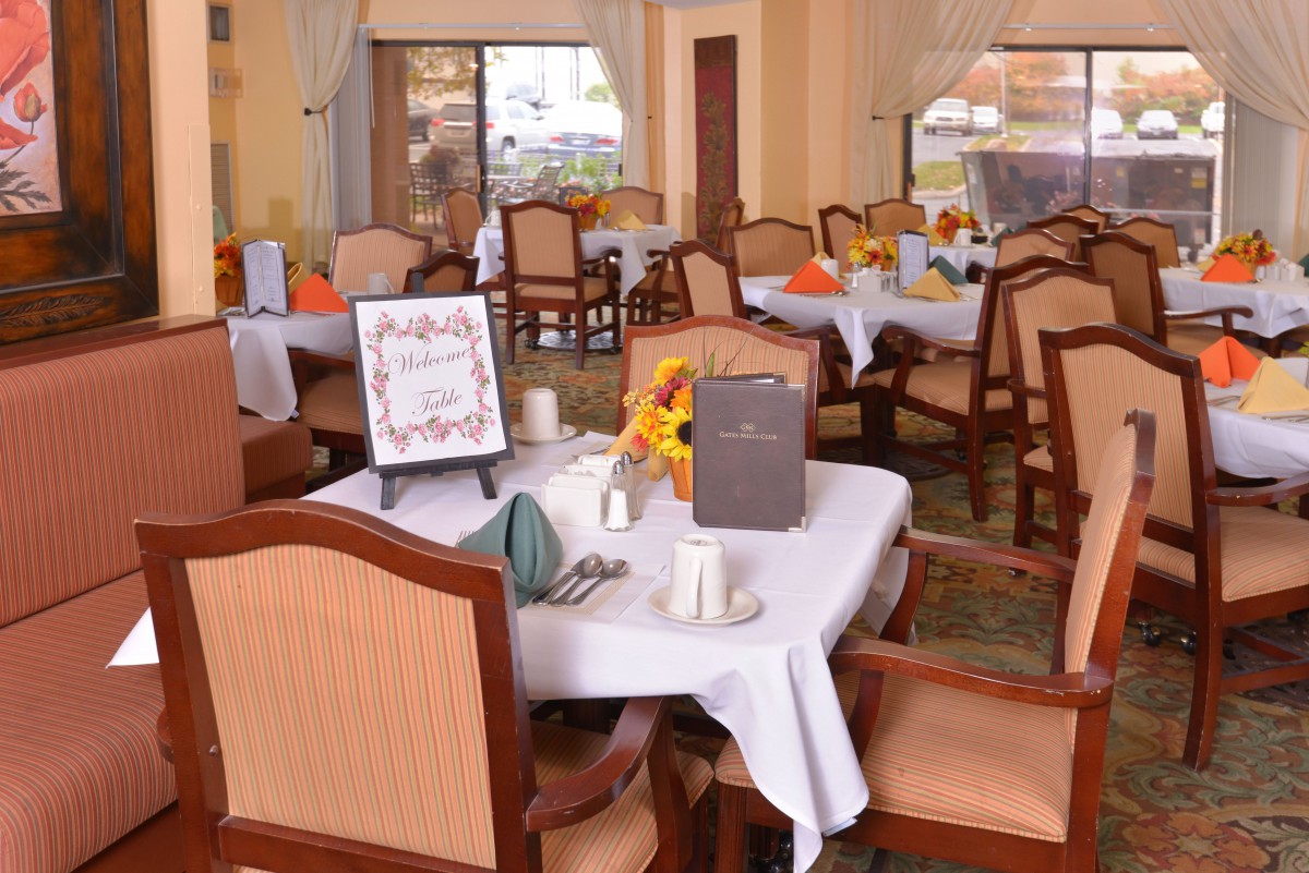 A cozy restaurant dining area with neatly arranged tables and chairs, featuring elegant table settings and floral decorations.