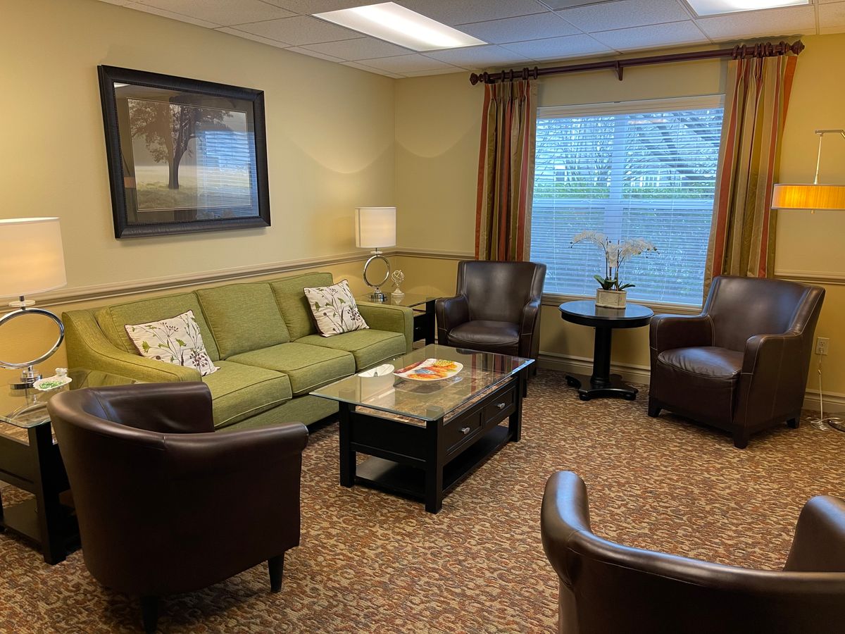 A cozy living room with a green sofa, leather chairs, and a coffee table.