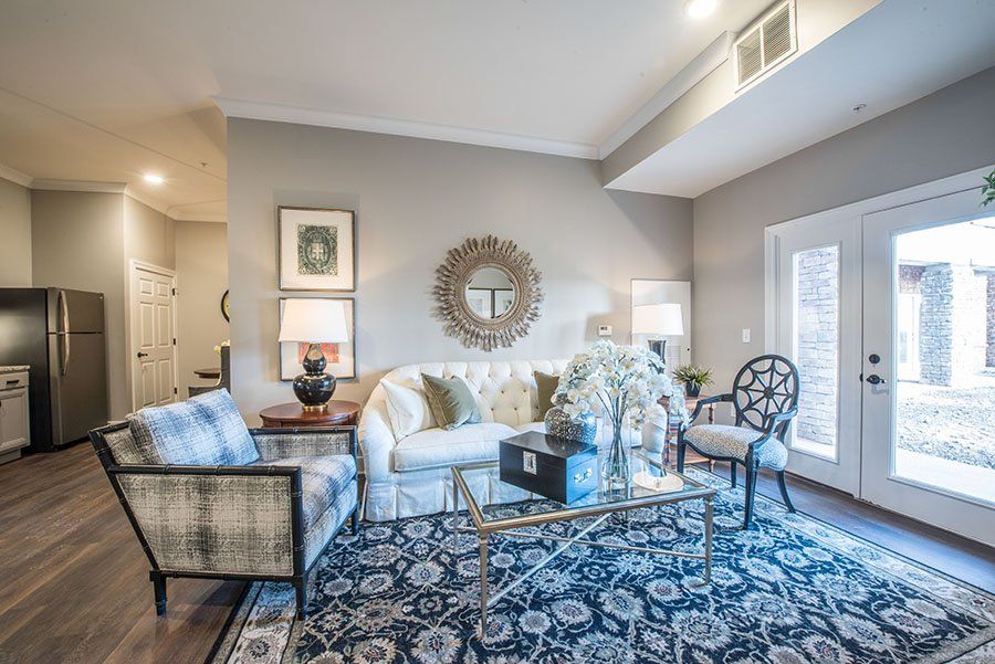 A stylishly decorated living room with a sofa, armchairs, and a patterned rug.