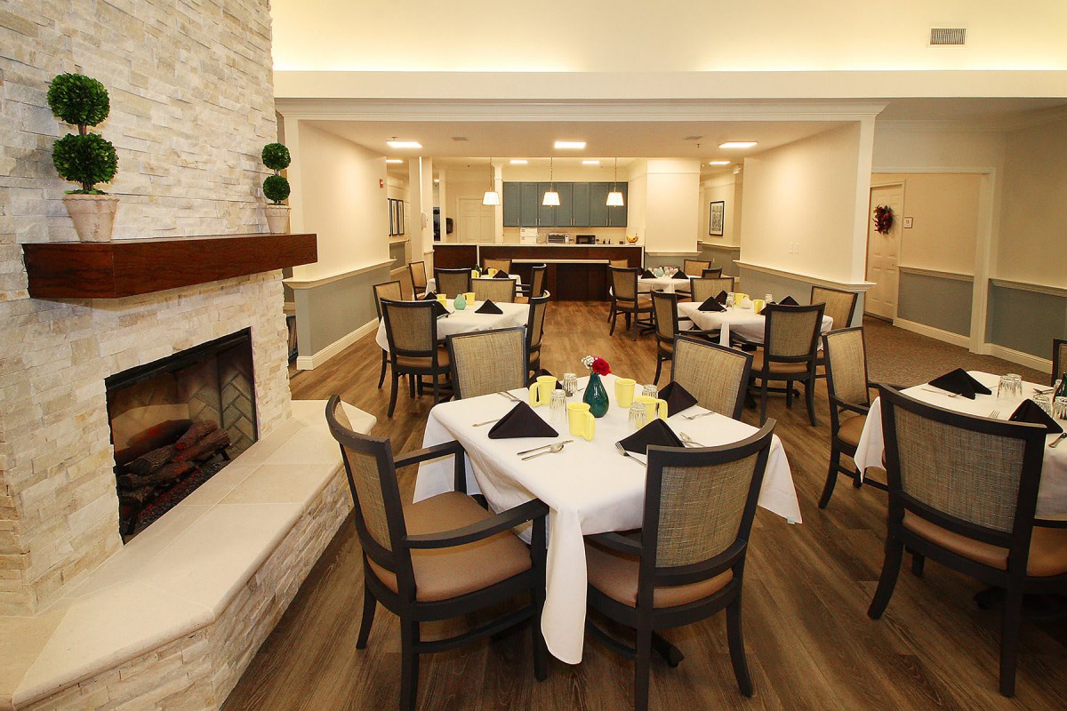 An elegant dining room with neatly arranged tables and chairs, featuring a cozy fireplace.