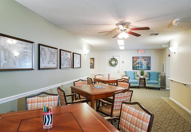 A cozy dining room with wooden tables and chairs, decorated with artwork and a ceiling fan overhead.