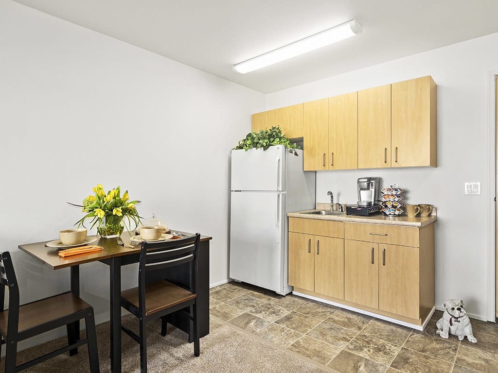 A small kitchen with a dining table, refrigerator, and cabinets.